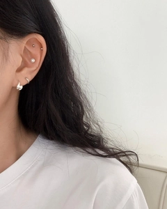 Close-up of minimalist 925 silver earring set with heart charm and pearl on ear