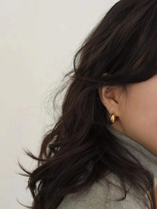 Close-up of elegant gold drop earrings on female model with minimalist style