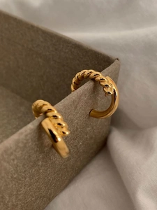 Detail of gold twisted rope hoop earrings resting on a minimalist jewelry box edge