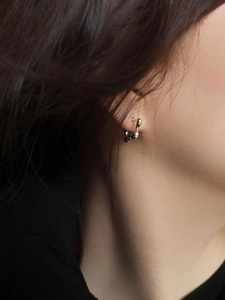 Detail of minimalist wavy 925 silver stud earrings on a model with liquid metal design