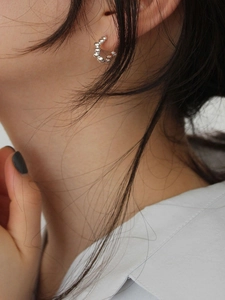 Close-up of minimalist S925 sterling silver beaded C-hoop earrings worn by a model