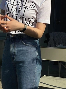 Detail of high-waisted dark blue straight jeans paired with a white printed graphic t-shirt