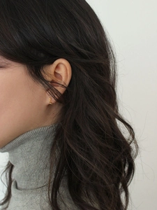 Minimalist gold huggie hoop earrings with twisted rope texture shown on a model