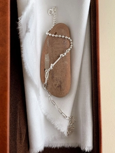 Minimalist S925 sterling silver knotted chain bracelet on smooth stone and linen background