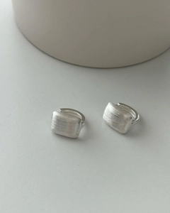Detailed view of rectangular silver earrings with a textured brushed matte metal finish