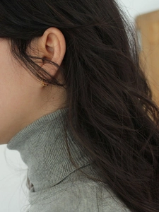 Detailed close-up of a twisted gold hoop earring worn for an elegant minimalist style