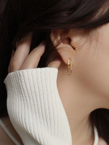 Close-up of 925 sterling silver gold-plated oval linked earrings with zircon on model