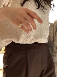 Detail of silver and gold mixed metal wide ring paired with chic beige knitwear
