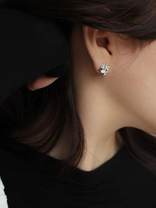 Detail of silver irregular earring with lava texture and crystal on model's ear