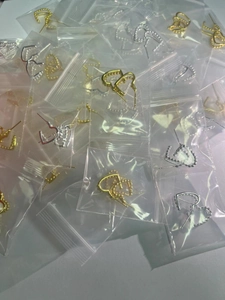 Stock di orecchini a doppio cuore in oro e argento mostrati in confezioni sfuse