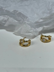 Detail of 925 sterling silver C-shaped double earrings with square clear gemstone