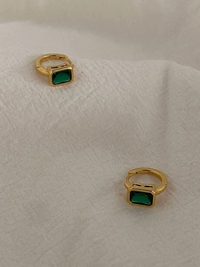 Macro shot of S925 hallmark on gold plated silver earrings with emerald green gemstones