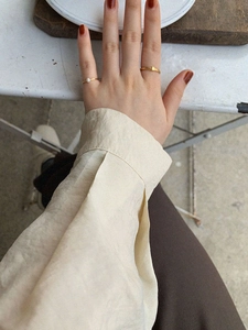 Minimalist stackable gold rings set with pearl accent on model hand in cozy setting