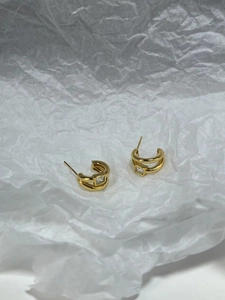 Detail of C-shaped gold-plated silver earrings featuring square cubic zirconia stones