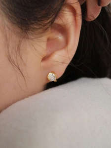 Macro detail of a 925 sterling silver gold-plated earring with sparkling round zircon