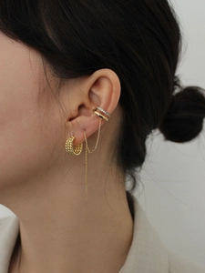 Detail of French vintage layered gold hoop earring with chain and zirconia ear cuff