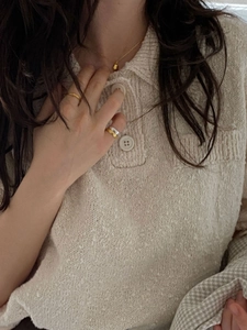 Minimalist beige knit polo shirt with gold teardrop necklace and stackable rings