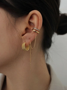 Detail of layered gold ear cuff with rhinestones and twisted hoop earring on model