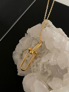 Close-up of gold U-link necklace with metal beads on natural white crystal cluster
