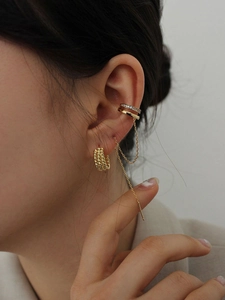 Close-up of a gold multi-layer twisted hoop earring with a delicate chain and crystal cuff