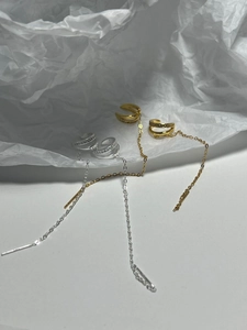 Close-up of gold and silver ear cuff earrings with long tassel chains and fine crystals