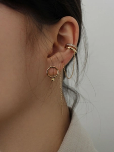 Detail of gold ear cuff earring with tassels and shimmering zircon studs on a model