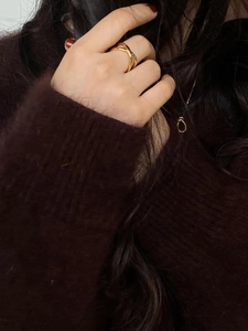 Minimalist double-layered gold crossover ring and knot necklace on a model in knitwear
