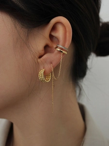 Close-up of gold ear cuff set with twisted hoop, zircon clip, and long tassel chain on model