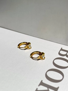 Macro view of gold S925 sterling silver huggie earrings with round cubic zirconia