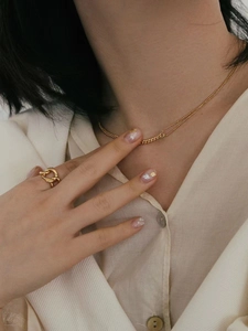 Elegant gold layered necklace and abstract twist ring set worn on a model's hand and neck