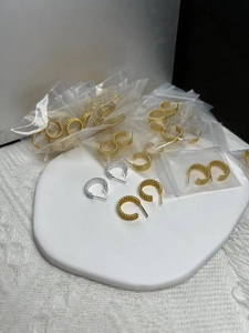 Detailed shot of twisted rope texture on silver C-shaped hoop earrings in gold and silver
