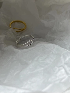 Detail view of gold and silver irregular double-layered open rings on white paper