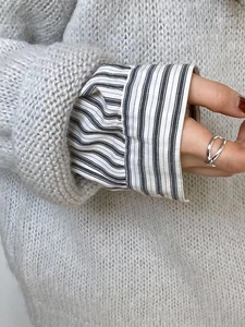 Close-up of a 925 sterling silver layered cross ring worn with a grey knit sweater