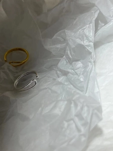 Close-up of minimalist gold and silver parallel double-line open rings on a paper surface