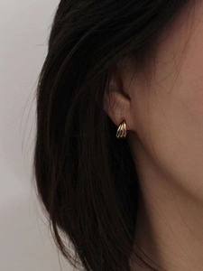 Eleganti orecchini a cerchio dorati a strati con texture a C indossati da modella
