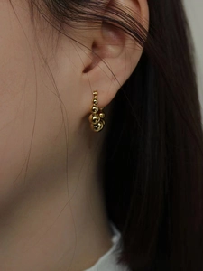Boucles d'oreilles créoles perlées dorées de style français portées par un mannequin