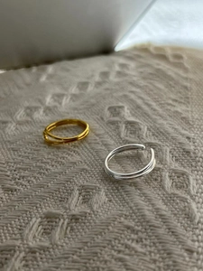 Detail of minimalist 925 sterling silver open rings in gold and silver on woven fabric