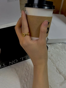 Close-up of a gold chain link ring on finger, featuring two interlocking oval loops design