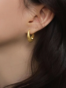 Élégantes boucles d'oreilles créoles gouttes dorées mates sur mannequin, effet brossé