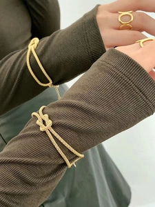 Detail of gold knotted bangles and geometric hollow rings worn on female hand