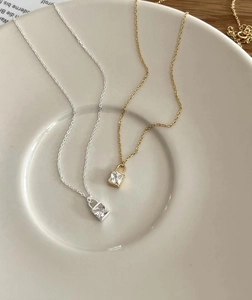 Détail de colliers cadenas en argent et or avec zircons carrés sur une assiette en céramique