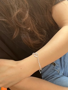 Detail shot of a minimalist 925 silver heart charm bracelet on a model wrist