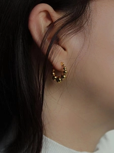 Boucles d'oreilles créoles dorées avec perles polies style français sur un mannequin