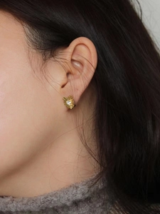 Close-up of heart-shaped gold earring with zircon stone worn on ear for detail