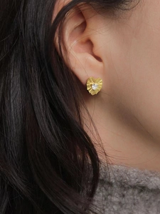 Macro shot of gold heart hoop earrings with radial texture and sparkling zircon