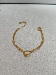 Detail of a minimalist 18K gold plated chain bracelet with an abstract heart charm pendant