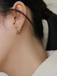 Boucles d'oreilles créoles en argent 925 doré avec trois zirconias verts sur modèle