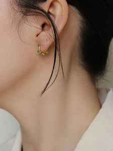 Boucles d'oreilles créoles dorées en argent 925 avec cinq zircons verts sur modèle