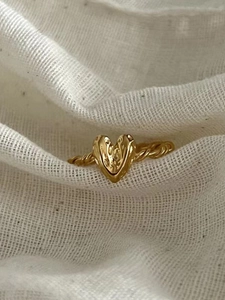 Macro shot of a vintage gold heart ring with a braided band on a soft linen background