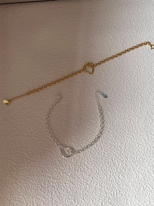 Close-up of gold and silver minimalist chain bracelets with asymmetric heart charms